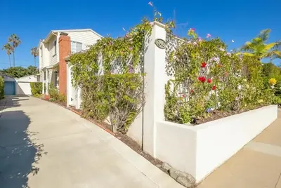 a white fence with flowers on it next to a sidewalk at Beach Happy in San Diego