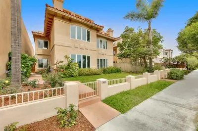 a house with a fence in front of a yard at Village and Views in San Diego