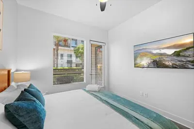 a white living room with a large tv on a wall at King Bed, Pool, Hot Tub, Arcade Room, Gym, Parking in San Diego