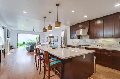a kitchen with wooden cabinets and a large island with bar stools at Rooftop Patio Hot Tub AC Beach & Bay Views in San Diego