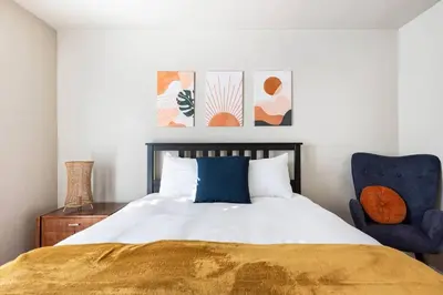 a bedroom with a bed and a blue chair at Charming Mid-Century Craftsman, Hot Tub with Serene Yard in San Diego