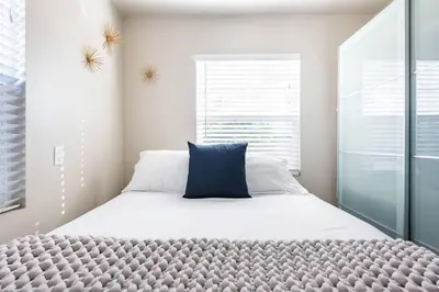 a bedroom with a large bed with a blue pillow on it at Charming Mid-Century Craftsman, Hot Tub with Serene Yard in San Diego