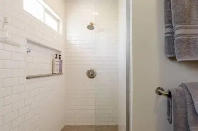 a bathroom with a shower with white tiles at Charming Mid-Century Craftsman, Hot Tub with Serene Yard in San Diego