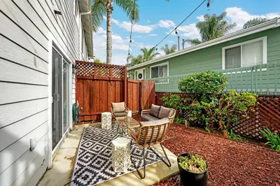a patio with a table and chairs and a fence at Beacons Beach Cottage in Encinitas