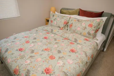 a bed with a floral comforter and pillows at 2 private masters, new beds & furniture, sleeps 12 in San Diego