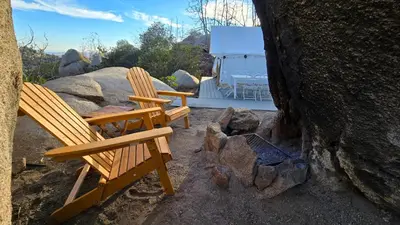 two wooden chairs sitting on top of some rocks at A Cozy Sunrise Glamping Escape with Panoramic View in Fallbrook