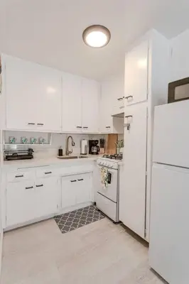 a white kitchen with white cabinets and a refrigerator at King Suite - Steps to Beach & Close to Pier in Oceanside