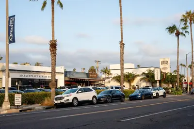 a row of cars parked in a parking lot with palm trees at Steps to Beach & Close to Restaurants and Shops in Oceanside