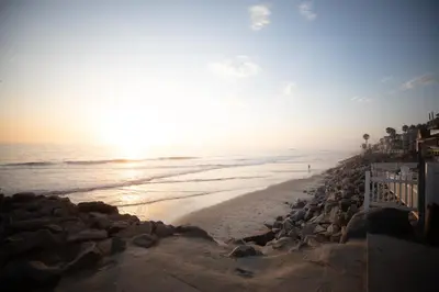 a beach with the sun rising over the ocean at Steps to Beach & Close to Restaurants and Shops in Oceanside