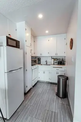 a kitchen with white cabinets and a refrigerator at Steps to Beach & Close to Restaurants and Shops in Oceanside