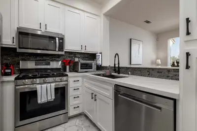 a kitchen with white cabinets and stainless steel appliances at Redecorated - Serene- Legoland- Family-Friendly in Carlsbad