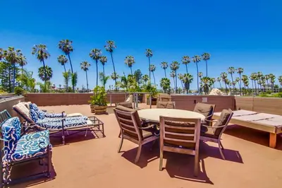 a patio with a table and chairs and palm trees at PACIFIC BEACH ESTATE water view in San Diego