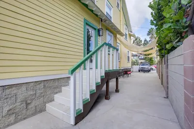 a sidewalk next to a yellow building with stairs at Steps to Balboa Park Sunny Historic Apartment in San Diego