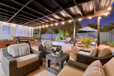 a patio with wicker chairs and tables and a kitchen at Massive 5BR Resort Style Retreat with Heated Pool in San Diego