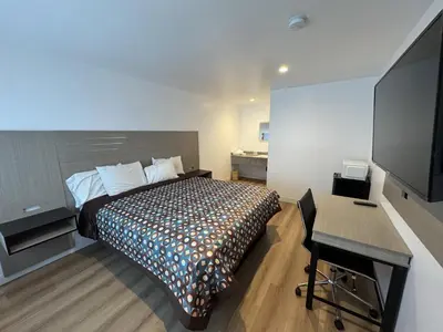 a bedroom with a bed and a desk and a flat screen tv at Sun Leisure Motel in Menifee