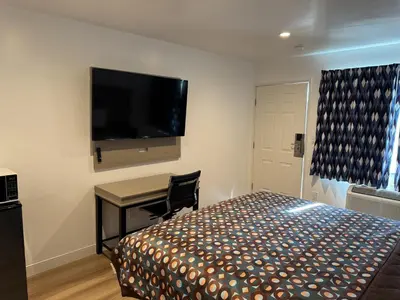 a bedroom with a bed and a desk and a flat screen tv at Sun Leisure Motel in Menifee