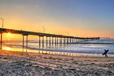 a person walking on the beach near a pier at 1 Block to Sand Stylish 3BR Contemporary Home in San Diego
