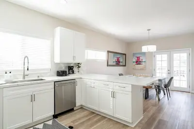 a kitchen with white cabinets and a dining table at 1 Block to Sand Stylish 3BR Contemporary Home in San Diego