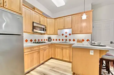 a kitchen with wooden cabinets and a stainless steel refrigerator at 1 Block to the Sand Stylish & Spacious Studio! in San Diego