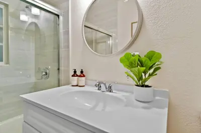 a white bathroom sink with a mirror and a plant at PB 3BR Beach Retreat Hot Tub Mini Golf in San Diego