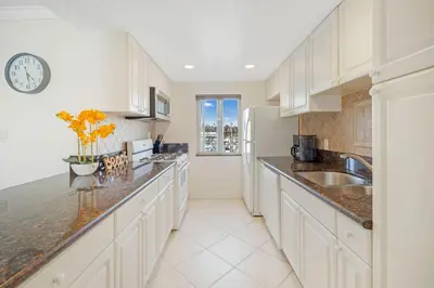a kitchen with white cabinets and a clock on the wall at Serene Harborfront Condo | Unbeatable Views & Coastal Charm in Oceanside