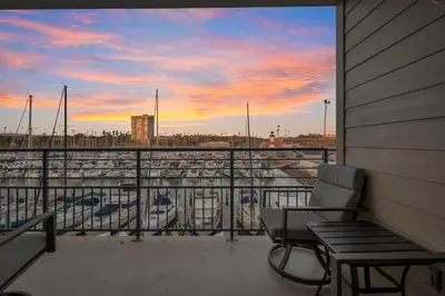 a balcony with a bench and a view of a marina at Serene Harborfront Condo | Unbeatable Views & Coastal Charm in Oceanside