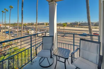 two chairs and a table on a balcony overlooking a parking lot at Oceanside Harbor Getaway | Steps to Sand, Shops & Restaurants in Oceanside