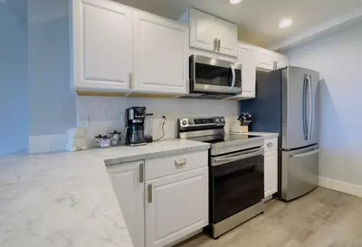 a kitchen with white cabinets and a black stove top oven at 2 bed 2 bath penthouse condo with AC and Ocean Views in San Diego