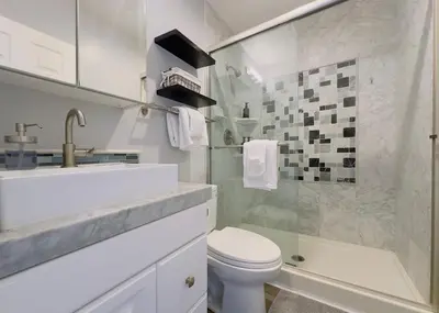 a white bathroom with a sink and a toilet at 2 bed 2 bath penthouse condo with AC and Ocean Views in San Diego