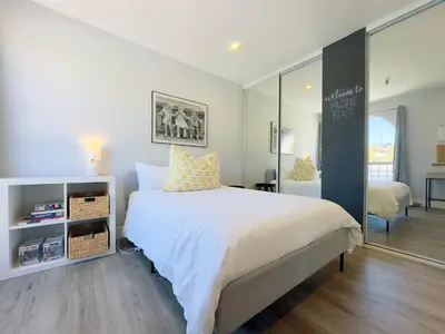 a bedroom with a large white bed and a mirror at 2 bed 2 bath penthouse condo with AC and Ocean Views in San Diego