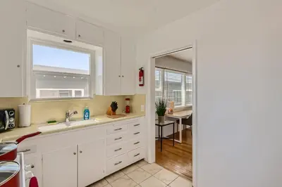a kitchen with white cabinets and a sink and a table at Walk to Beach - KING Apt In #1 Area - AB in San Clemente