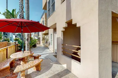 a patio with two tables and a red umbrella at Stroll to Shore and Mission Blvd Dog-Friendly Home in San Diego
