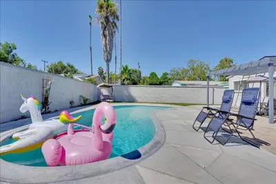 a swimming pool with a pink inflatable flamingos and chairs at Double Flamingo HotTub BBQ Game Room Self Check-in in San Diego