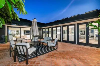 an outdoor patio with chairs and an umbrella at Pacific Perfection - Ocean Views Jacuzzi Walk to Beach and Dining in San Diego