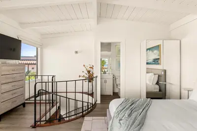 a bedroom with a bed and a spiral staircase at Pacific Perfection - Ocean Views Jacuzzi Walk to Beach and Dining in San Diego