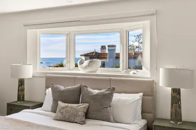 a bedroom with a bed and a window with the ocean at Pacific Perfection - Ocean Views Jacuzzi Walk to Beach and Dining in San Diego