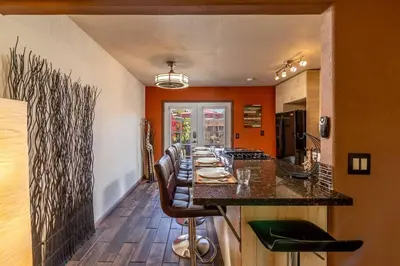 a kitchen with orange walls and a bar with leather chairs at Giraffe House in Chula Vista