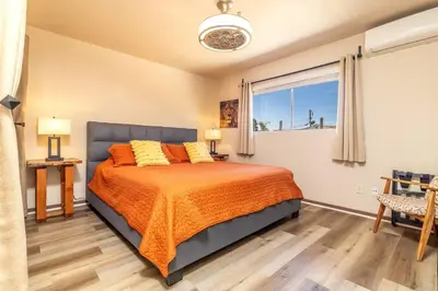 a bedroom with a bed with orange sheets and a window at Giraffe House in Chula Vista