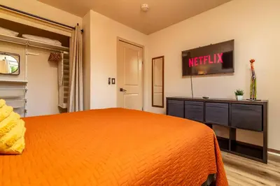 a bedroom with an orange bed and a tv at Giraffe House in Chula Vista