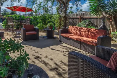 a patio with a couch and a chair and an umbrella at Giraffe House in Chula Vista