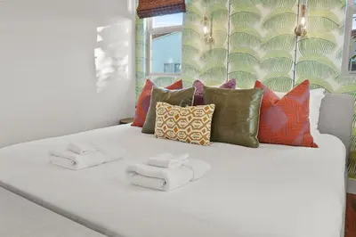 a white bed with pillows and towels on it at Village Vistas - Walk to Beach and LJ Village, AC, Spa in San Diego