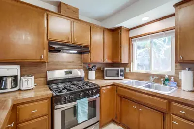 a kitchen with wooden cabinets and a stove and a sink at Tidal Wave 1 in San Diego