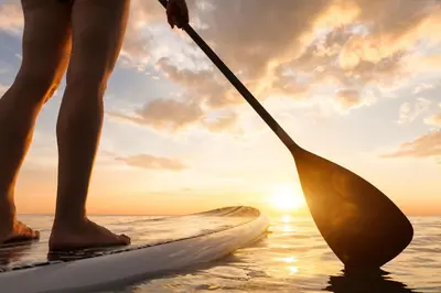 a person standing on a paddle board in the water at Tidal Wave 1 in San Diego