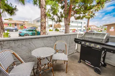a grill and chairs on a patio with trees at Local Gem 1 in San Diego
