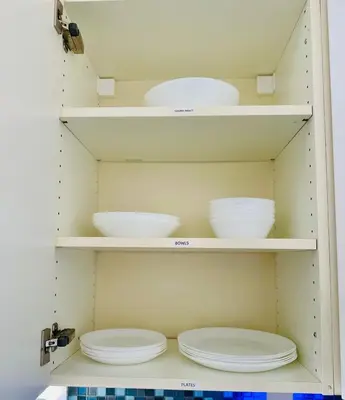 two white plates and bowls on shelves in a kitchen at 3-Bedroom, Prime Location, Private Backyard! in San Diego