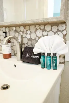 a bathroom counter with a sink with two bottles of makeup at Oceanside Beach Condos in Oceanside