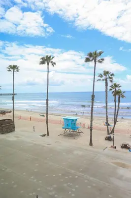 a picnic table on a beach with palm trees at Oceanside Beach Condos in Oceanside