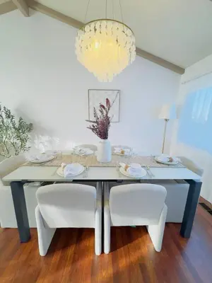 a dining room table with white chairs and a chandelier at Del Mar Coastal Haven in San Diego