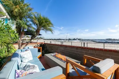 a patio with couches and a fire pit and the beach at Bayfront Apartment Steps to the Sand - Ultimate Coastal Living in San Diego