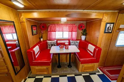 a small dining room with red chairs and a table at Darling Daisy Retro RV Adventure in El Cajon